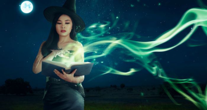 a young white woman in a witch's hat with a book