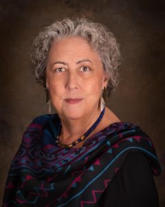 Portrait of person with short, curly hair wearing a multicolored scarf.