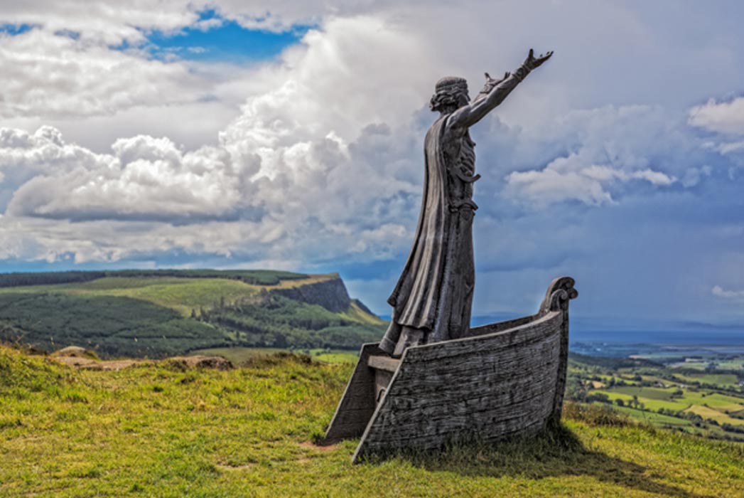 sculpture of Celtic god with arms raised looking out to sea